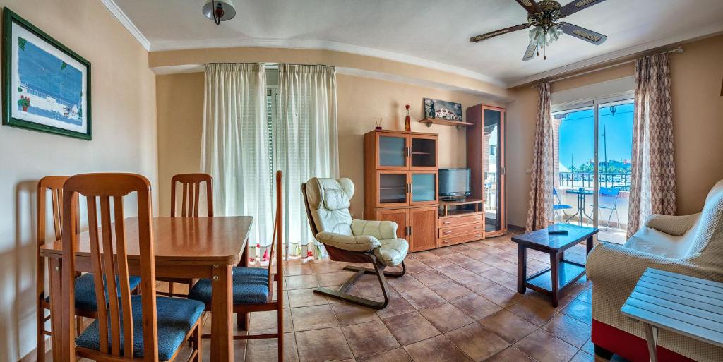 a living room with a table and chairs and a television at Apartamento 2 dormitorios en la mejor zona de Roquetas in Roquetas de Mar