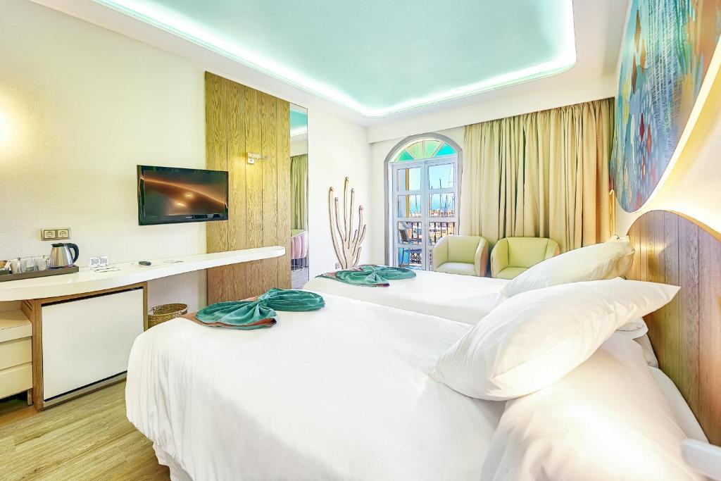 a hotel room with two beds and a desk at Hotel LIVVO Puerto de Mogán in Puerto de Mogán