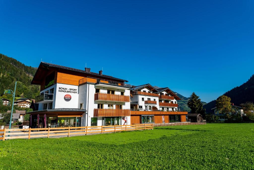 un edificio con un campo verde delante de él en Appartement-Pension Kendlbacher, en Grossarl