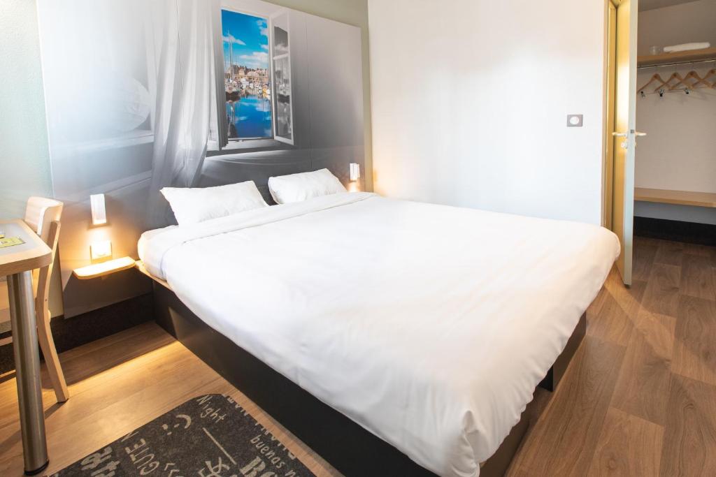 a large white bed in a small room at B&B HOTEL Saint-Malo Centre in Saint Malo