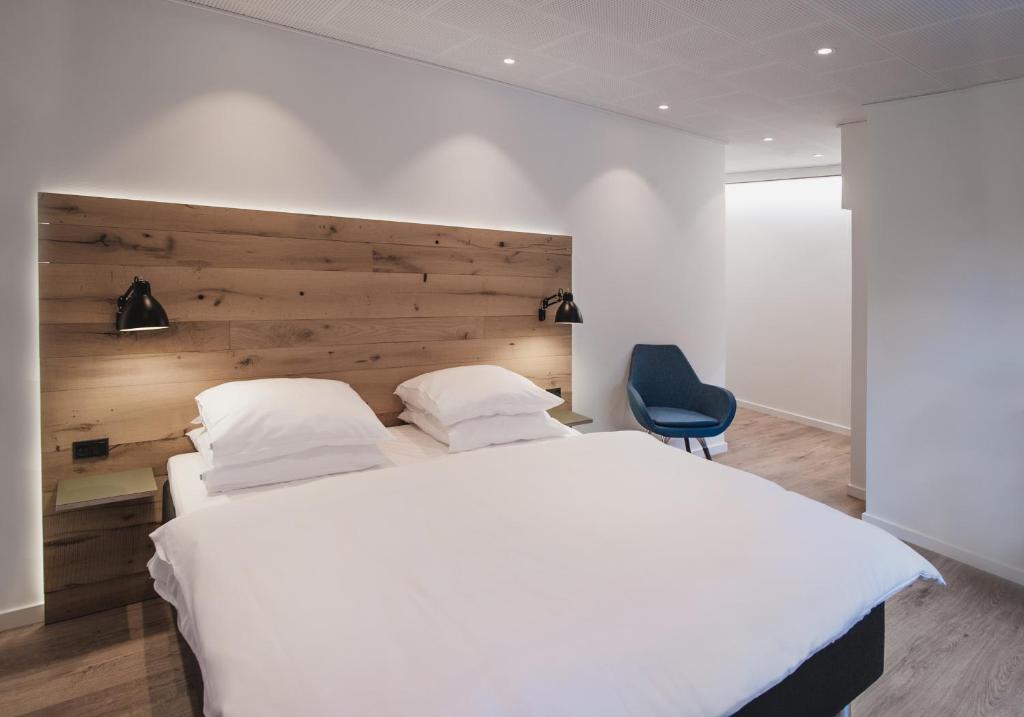 a bedroom with a large white bed and a blue chair at Hotel Town Living in Ringkøbing