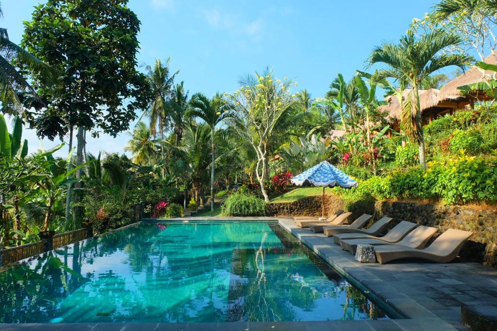 a swimming pool with lounge chairs next to a resort at Puri Taman Sari in Tabanan