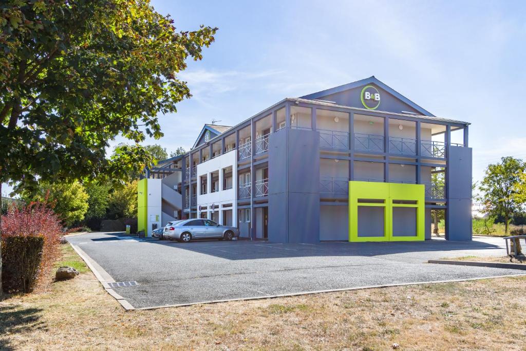 a building with a car parked in front of it at B&B HOTEL TOURS Sud Joué-lès-Tours in Joue-les-Tours