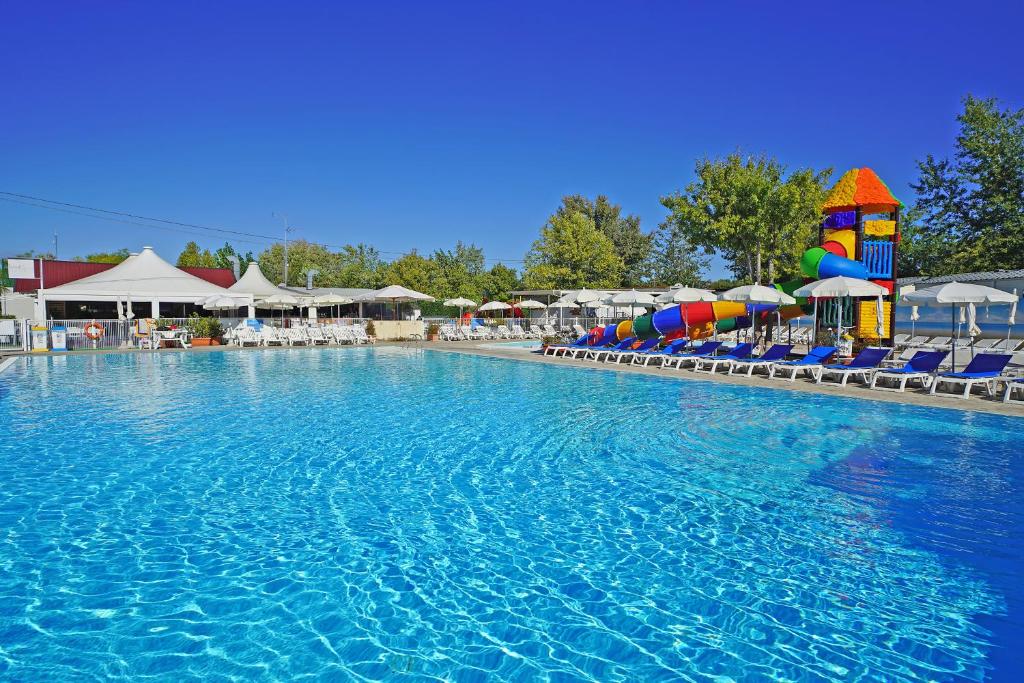 una piscina in un resort con sedie e ombrelloni di Butterfly Camping Village a Peschiera del Garda