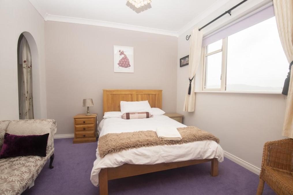 1 dormitorio con cama, ventana y silla en Poppyfield House, Kenmare en Kenmare