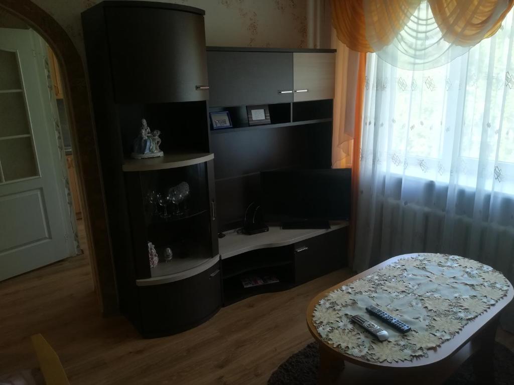 ein Wohnzimmer mit einem Tisch und einem Fenster in der Unterkunft Апартамент в центре города, Stacijas 111 in Daugavpils