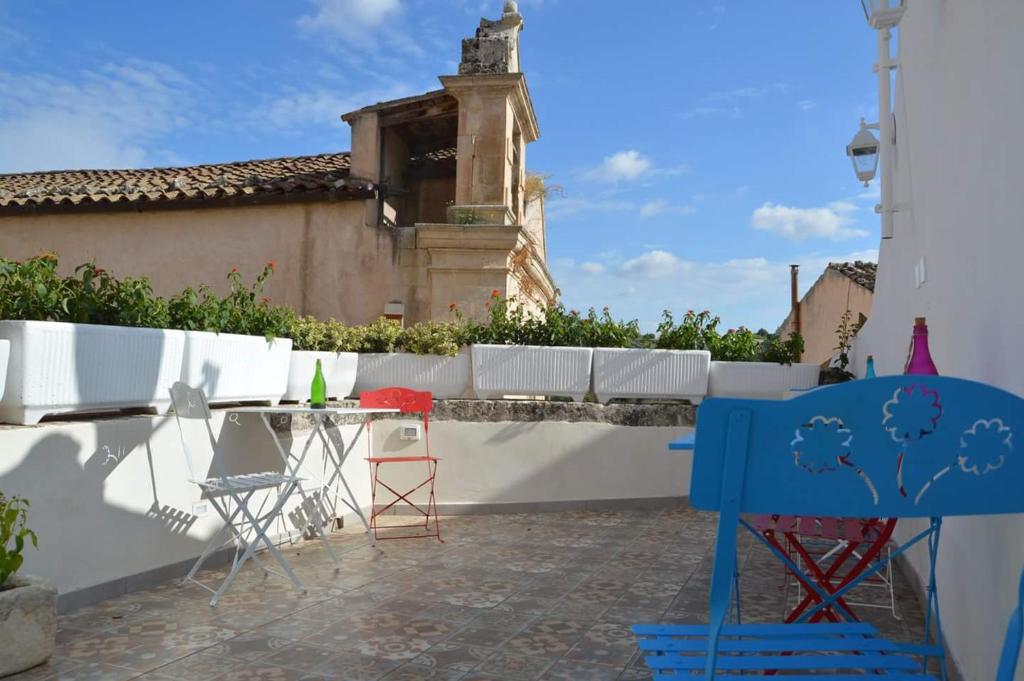 a patio with chairs and a table in front of a wall at Lucernaio Rooms in Ragusa