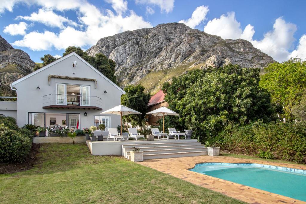 a house with a swimming pool in front of a mountain at Protea & Pincushion Cottages in Hermanus