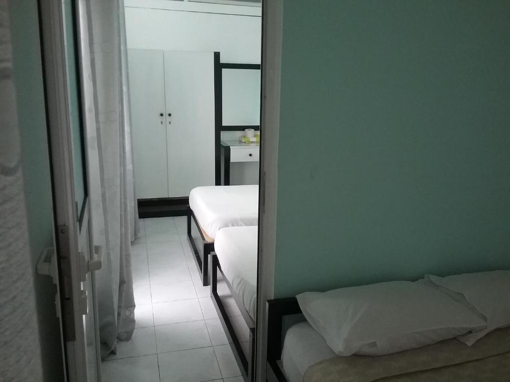 a small room with two beds and a mirror at La Plaine Verte Guesthouse in Port Louis