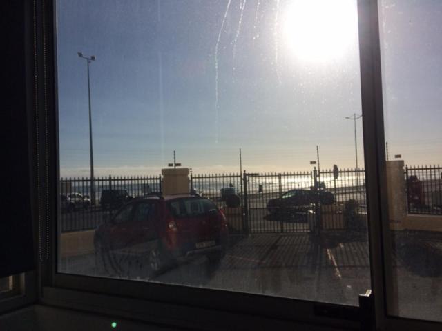 una ventana con vistas a un aparcamiento con coche en Romilly Beach Apartment, en Strand
