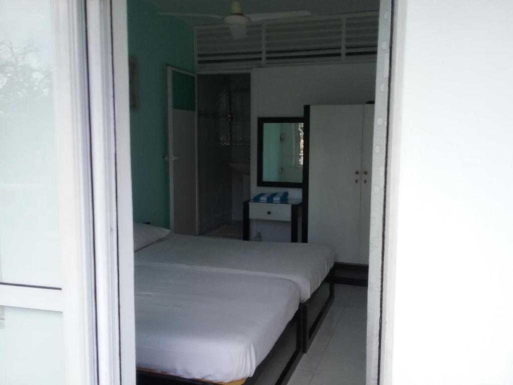 a bedroom with a white bed and a window at La Plaine Verte Guesthouse in Port Louis