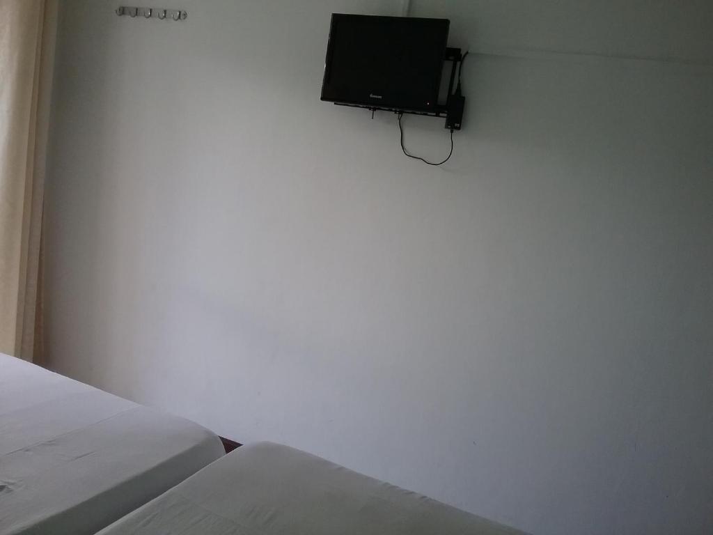 a bedroom with two beds and a tv on the wall at La Plaine Verte Guesthouse in Port Louis