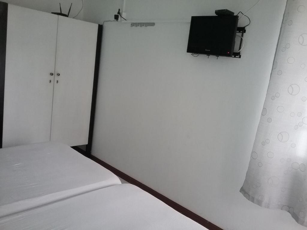 a bedroom with a bed and a tv on a wall at La Plaine Verte Guesthouse in Port Louis