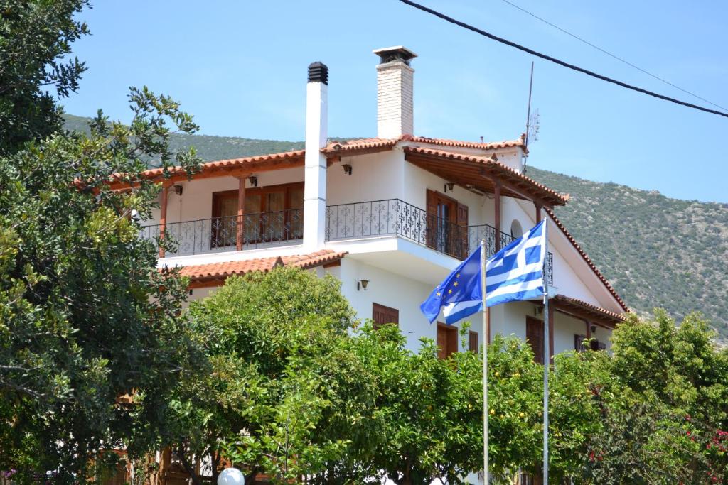 a white house with a flag in front of it at Dimitras House in Paralio Astros