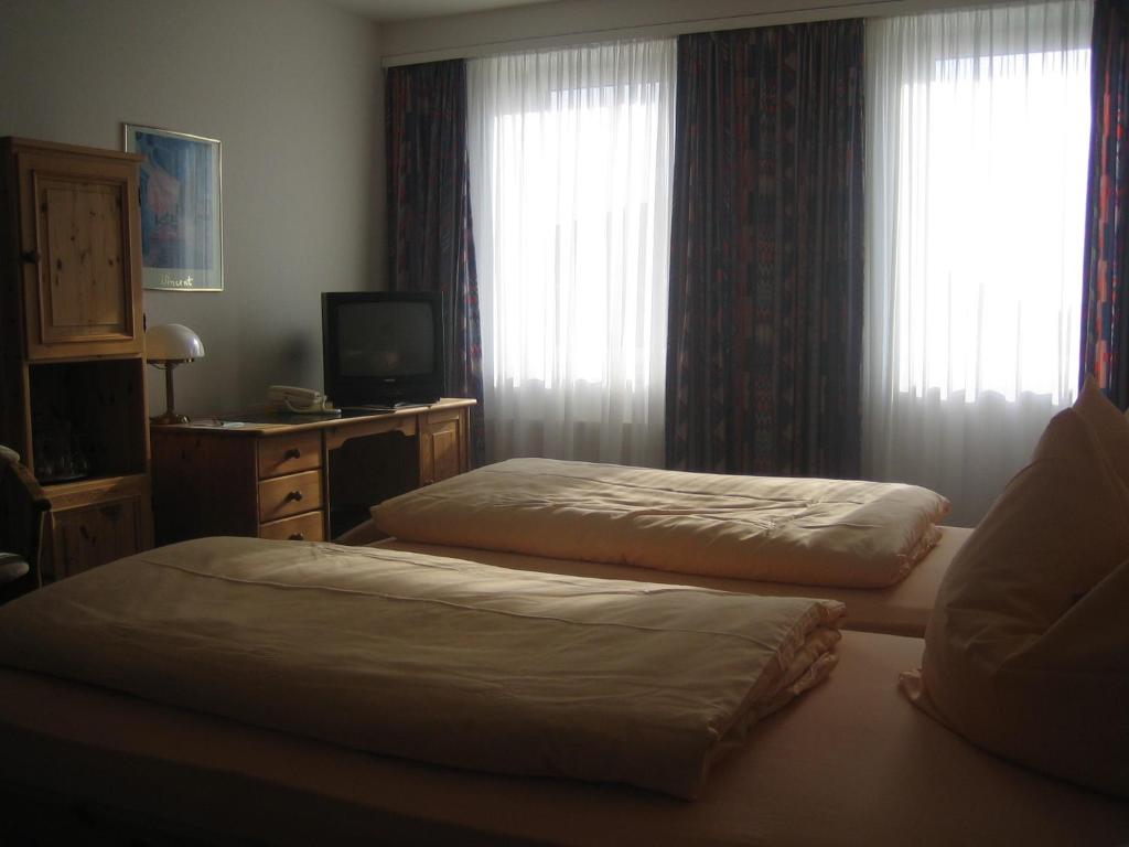 a hotel room with two beds and a television at Neustädter Hof Hotel Garni in Neustadt am Rübenberge