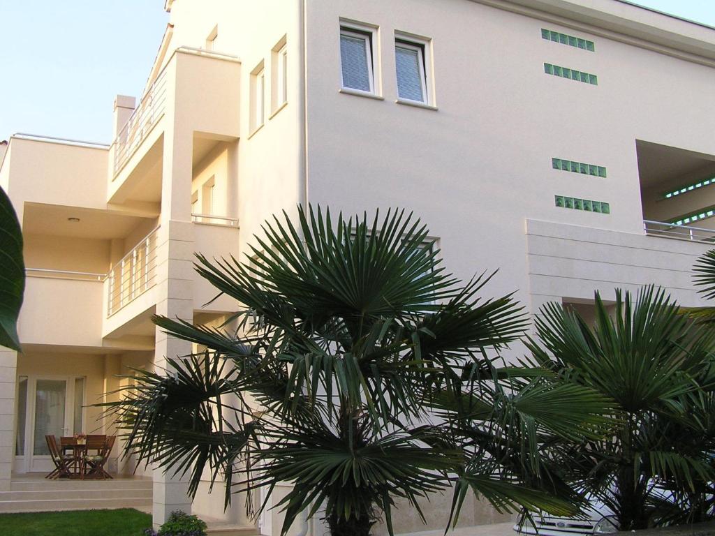 a building with palm trees in front of it at Apartments Oaza Regi in Medulin