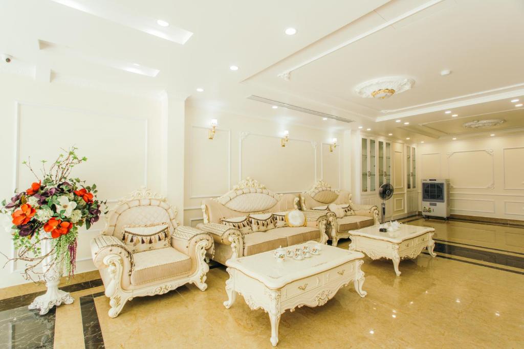 salon z białymi meblami i wazą kwiatów w obiekcie White Crown Hotel w Ha Long
