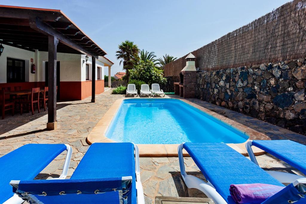 una piscina con sillas azules junto a una casa en Casa La Vera, en La Oliva