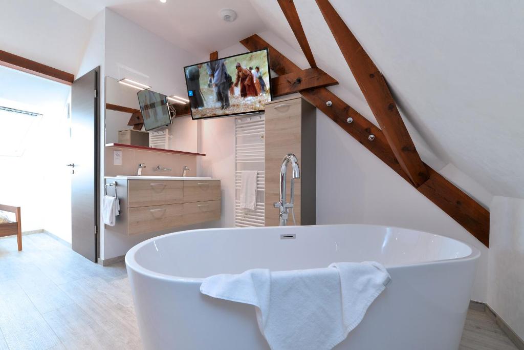 een badkamer met een wit bad en een tv bij Les Suites Du Cygne in Colmar