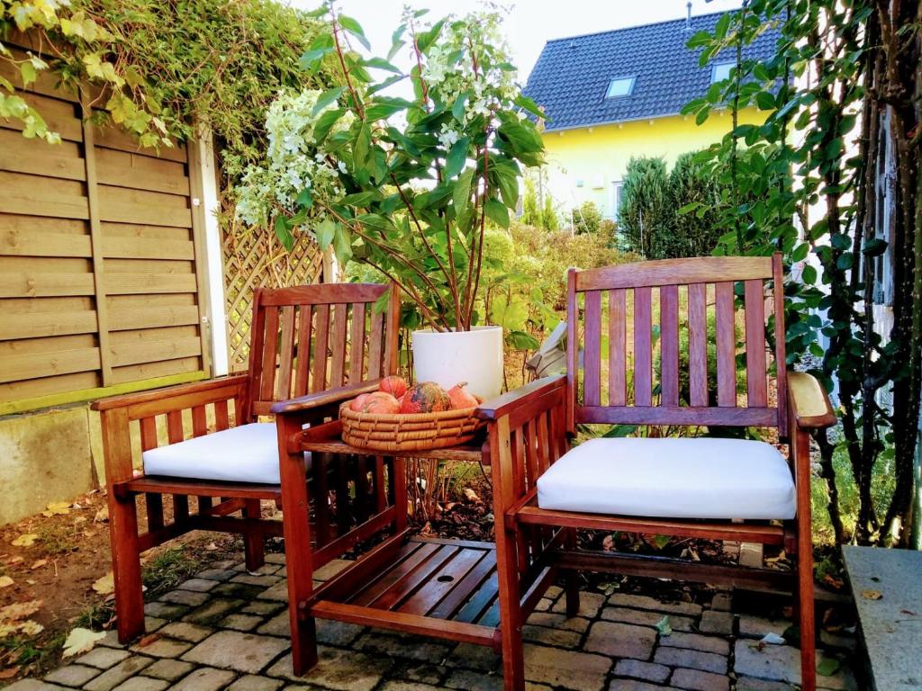 2 sedie in legno sedute su un patio con cesto di frutta di Art & Nature Apartments in der Nähe FFM-Messe a Bad Vilbel