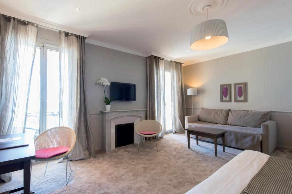 a living room with a couch and a fireplace at Hôtel Le Royal Promenade des Anglais in Nice