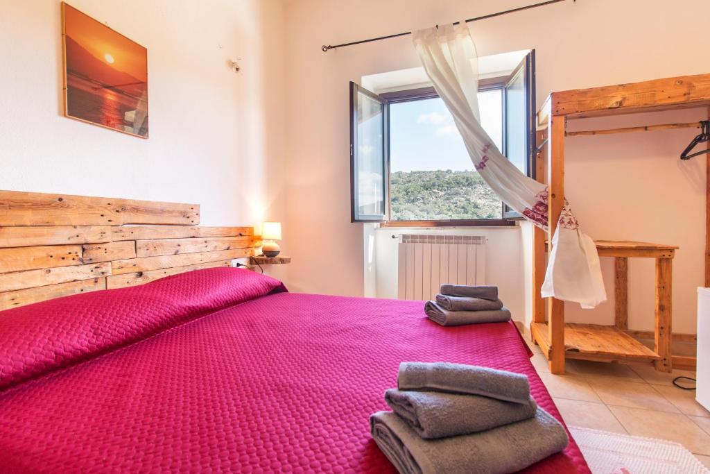 Un dormitorio con una gran cama rosa y una ventana en Ristoro Norghio, en Irgoli