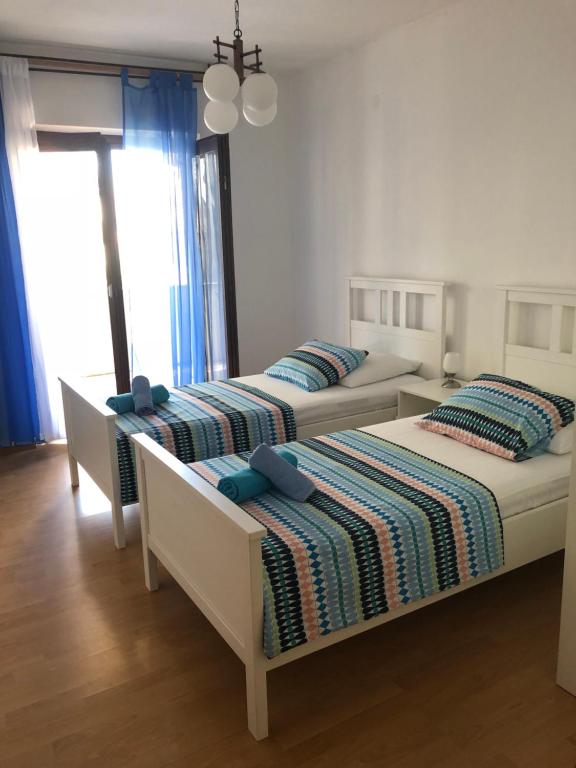 two beds in a bedroom with blue pillows at Apartmani Eta in Pag