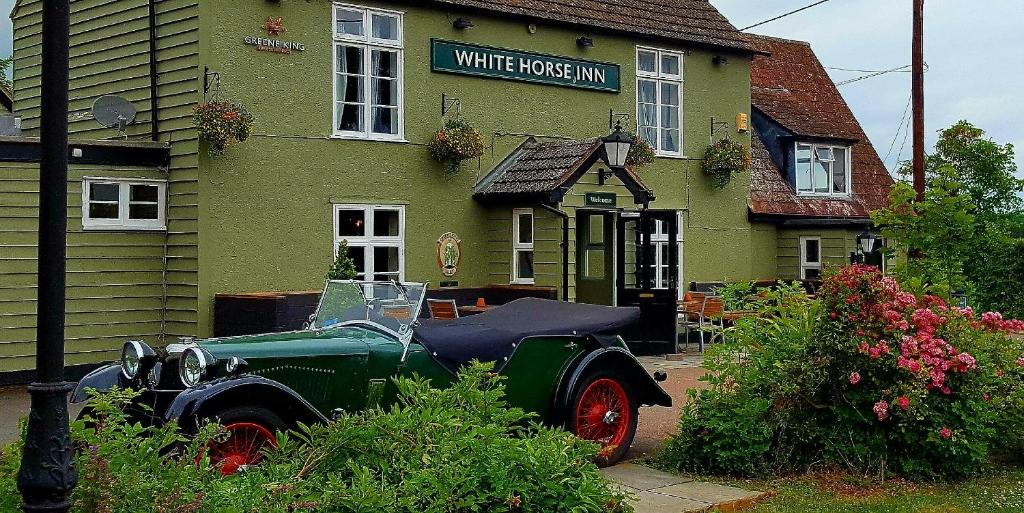 an old green car parked in front of a white horse inn at The White Horse Inn in Cambridge