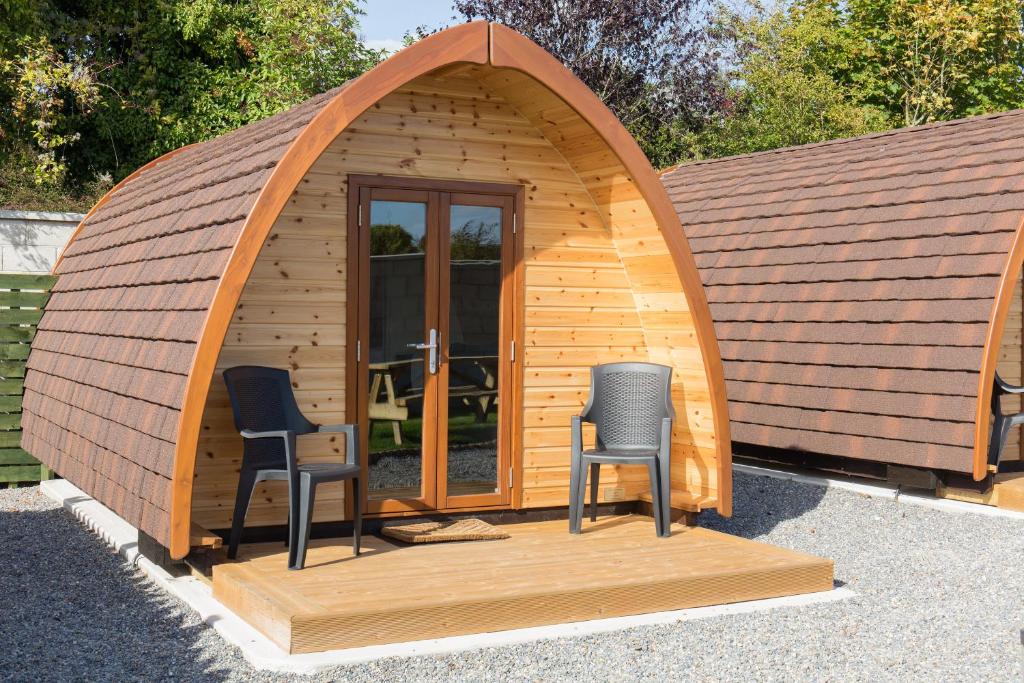 a small wooden iguana building with two chairs in it at Blackwater Eco Pods in Villierstown