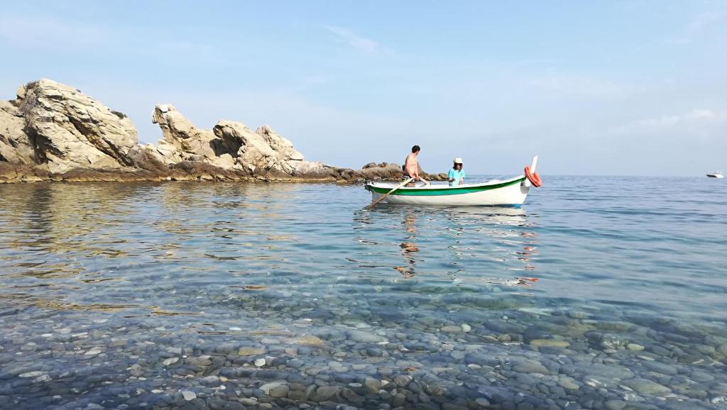 dwoje ludzi w małej łodzi w wodzie w obiekcie La Casetta w mieście Mortola Inferiore