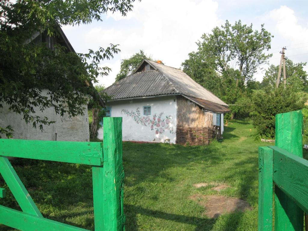 une grange avec une clôture verte devant elle dans l'établissement Дибинецькі Карпати, à Dybintsy