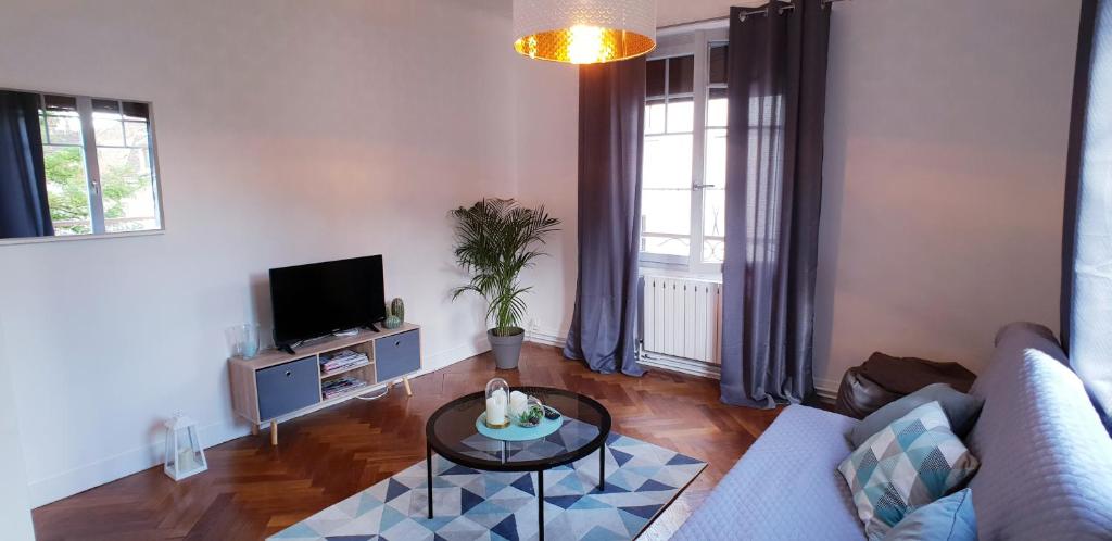 uma sala de estar com um sofá e uma mesa em Au 36, Les Apparts Hotel Joigny em Joigny