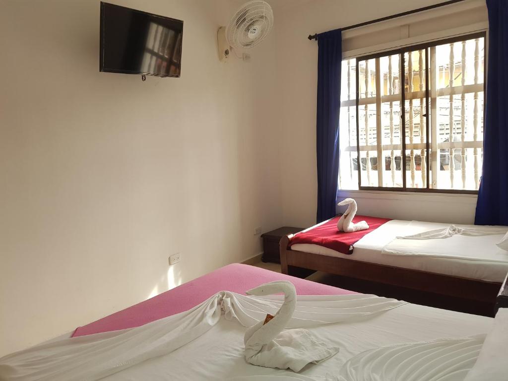 a hotel room with two beds and a window at Artur Hostel in Cartagena de Indias