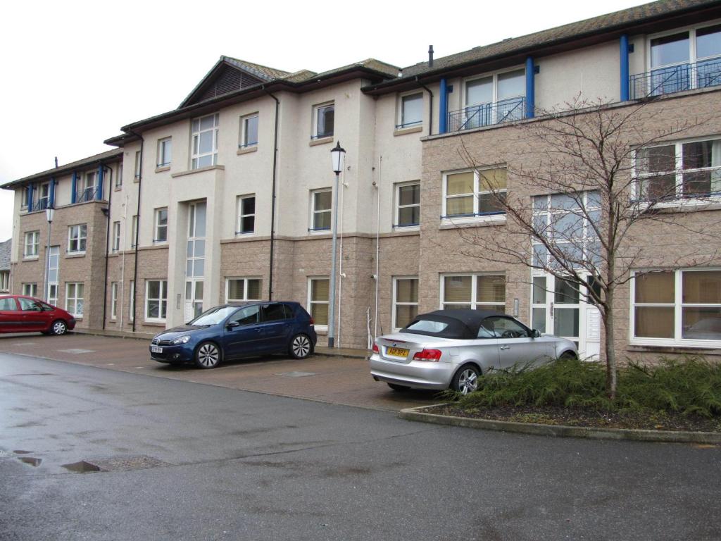 two cars parked in a parking lot in front of a building at River Walk Inverness in Inverness