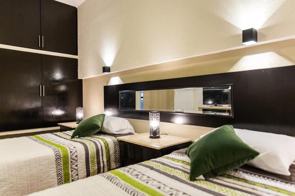 2 camas con almohadas verdes en una habitación de hotel en Departamento familiar, en Playa del Carmen