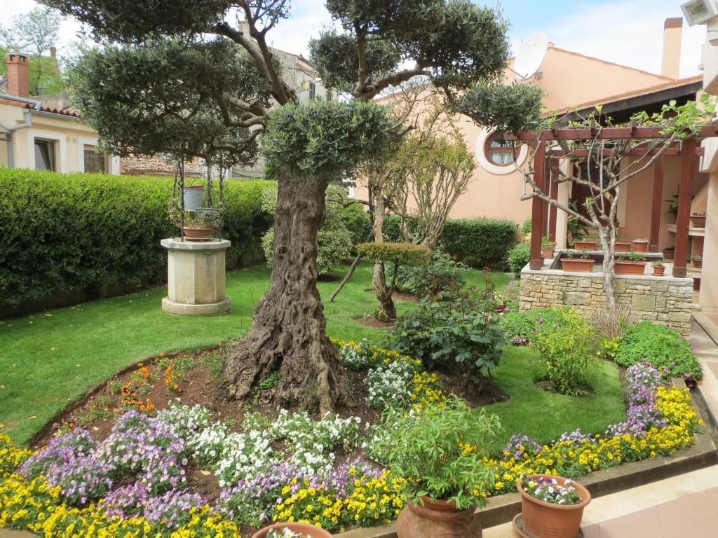 un jardín con un árbol y flores frente a una casa en Apartments Mediteraneo, en Tar