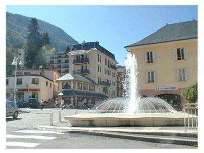 a fountain in the middle of a city with buildings at Hotel Le Centre in Brides-les-Bains