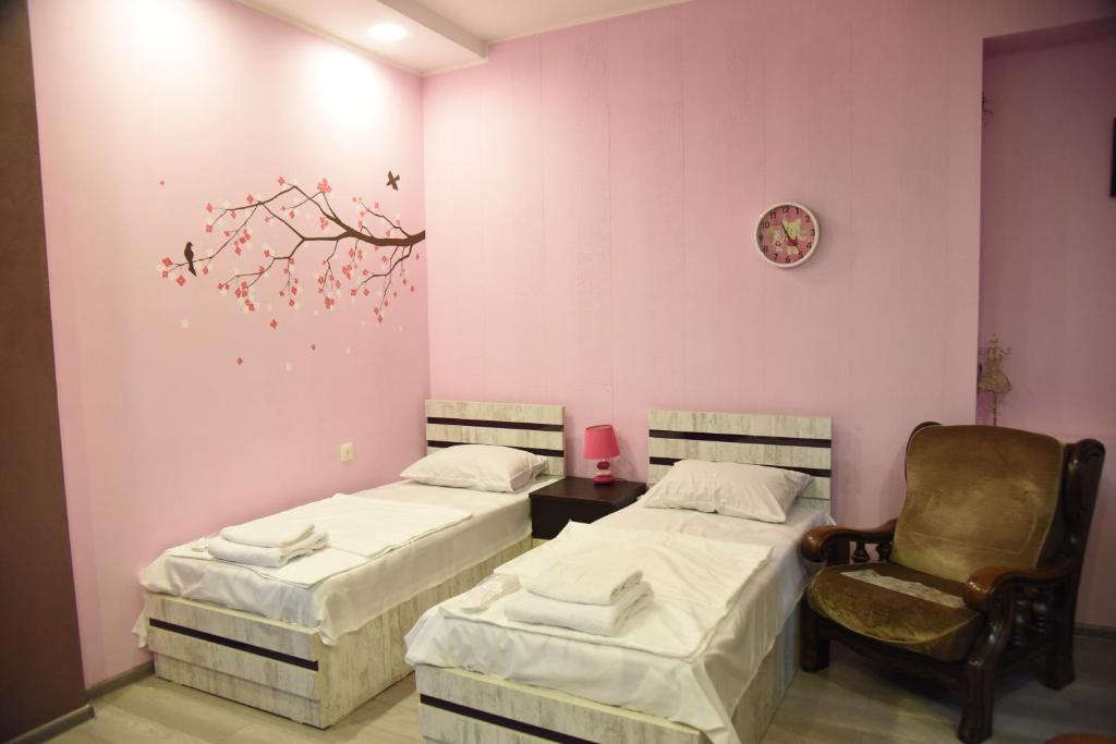 2 Betten und ein Stuhl in einem Zimmer mit rosa Wänden in der Unterkunft Panorama of Tbilisi in Tbilisi City