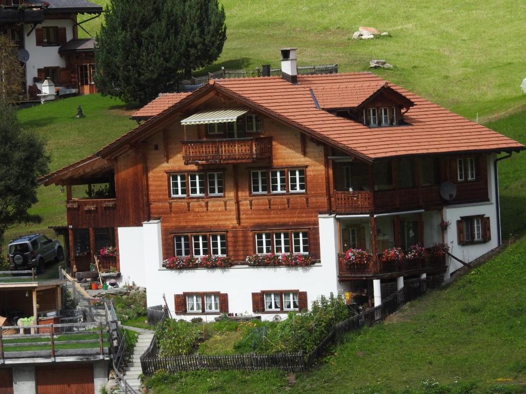 a large wooden house on a hill with flowers at Sertig Ferienwohnung in Davos
