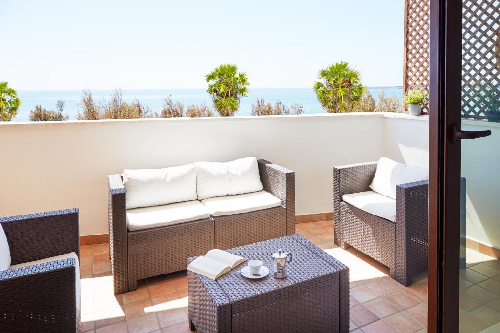 un patio con 2 sedie e un tavolo sul balcone di Aura CaseSicule, only for Sea View Lovers, Modern Style Apartment in City Center, Wi-Fi a Pozzallo