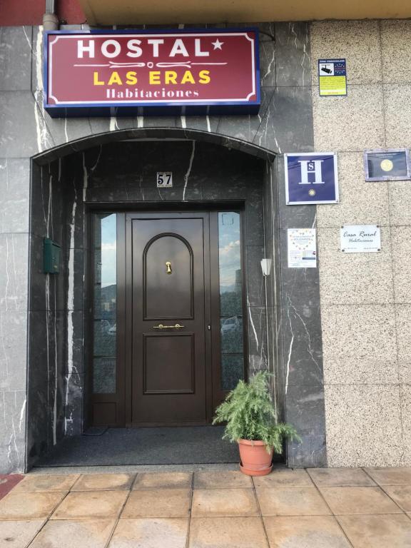 un edificio con una puerta y una planta delante en Hostal Las Eras, en Cubillos del Sil