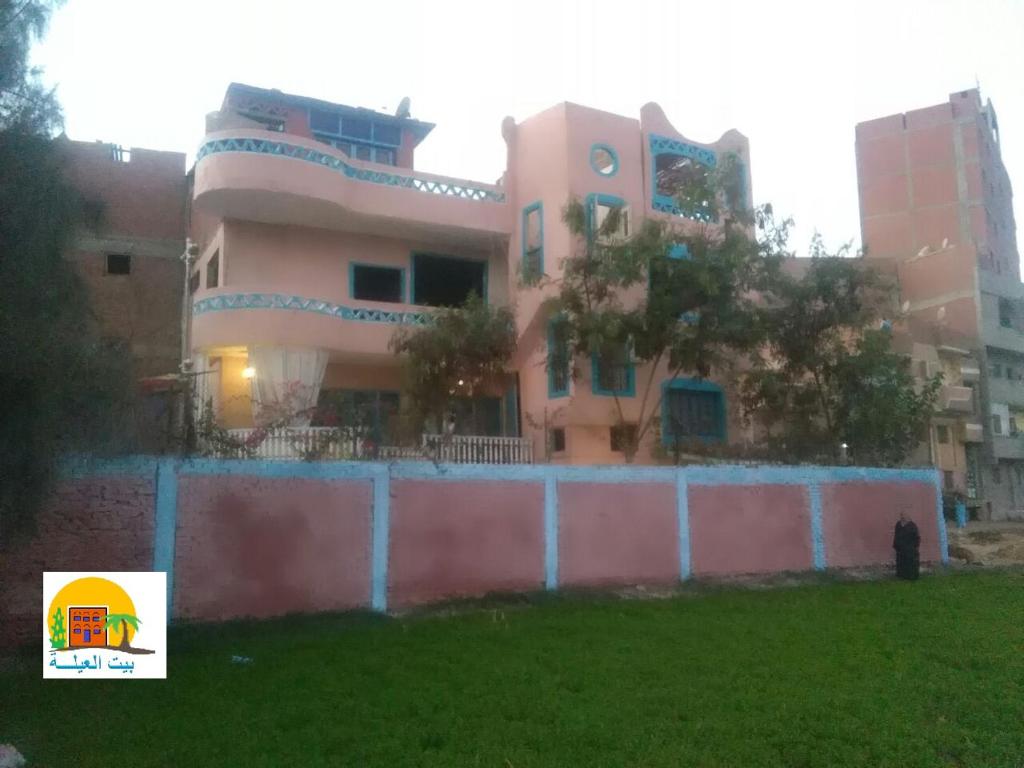 Um edifício cor-de-rosa com uma vedação à frente. em Rural Guest House فندق البيت الريفي em Tanta