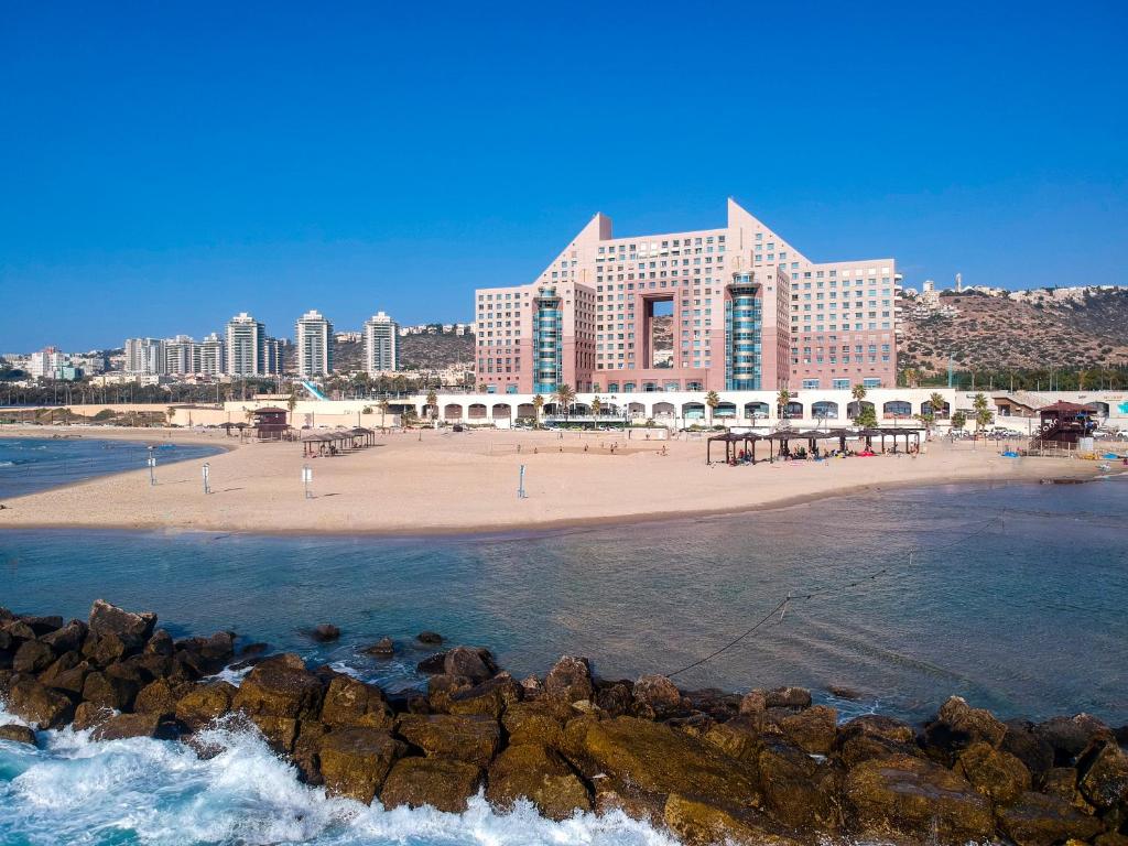 een uitzicht op een strand met een groot gebouw bij Almog Haifa Israel Apartments מגדלי חוף הכרמל in Haifa