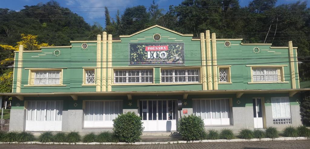 a green and white building with a sign on it at Pousada ECO in Corupá