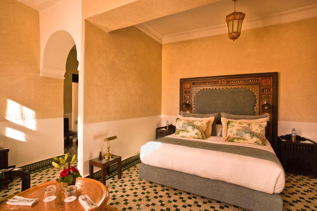 Riad Fes - Relais & Châteaux في فاس: غرفة نوم بسرير كبير وطاولة