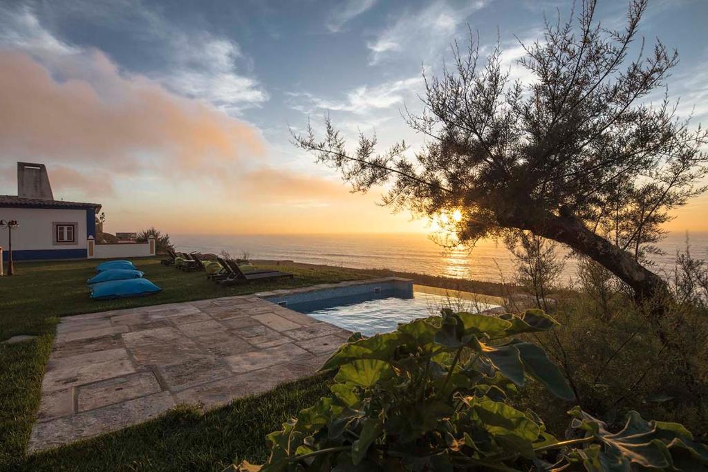 a backyard with a swimming pool and a tree at Chalet O Amorzinho Sintra Praia in Sintra