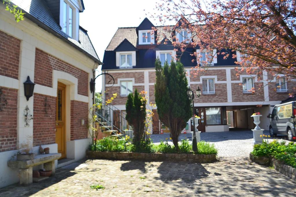 une cour d'une maison avec un arbre et un bâtiment dans l'établissement Coq hôtel, à Montreuil-sur-Mer