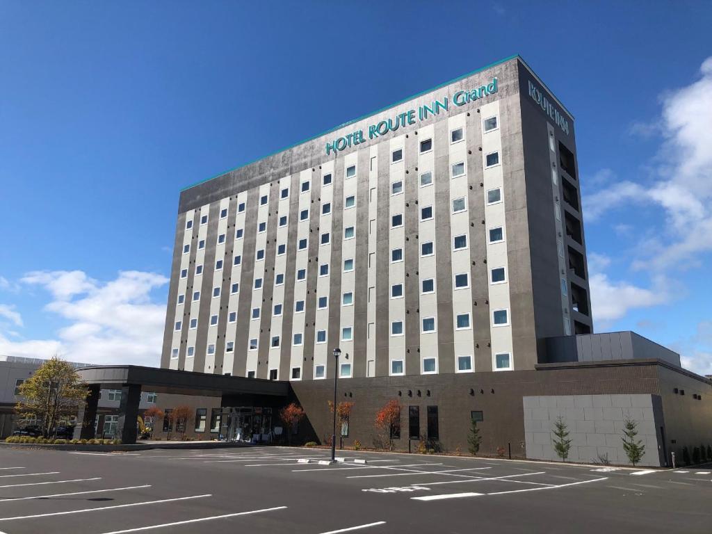 un edificio con un estacionamiento delante de él en Hotel Route-Inn Grand Muroran, en Muroran