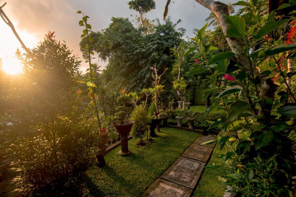 un jardín con plantas verdes y puesta de sol en Ubud Wins Bungalow, en Ubud