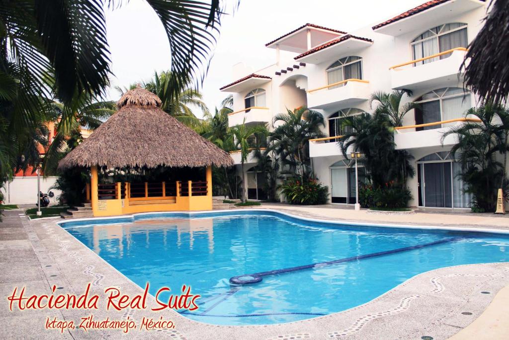 a swimming pool in front of a building at Hacienda Real Suits Ixtapa in Ixtapa